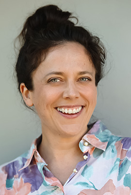Das Portrait zeigt Amanda Mitrevski mit mittellangen, schwarzen Haaren und einem dezenten Lächeln.